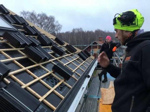 Personal installerar svarta takpannor